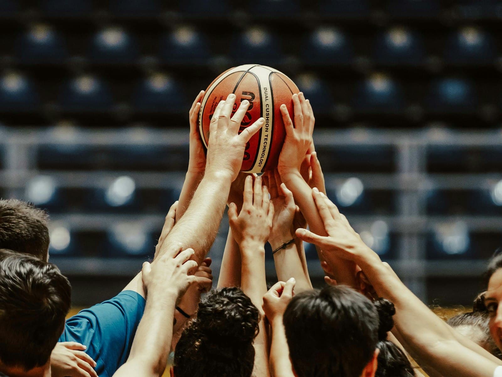 Teammates reaching for a basketball together